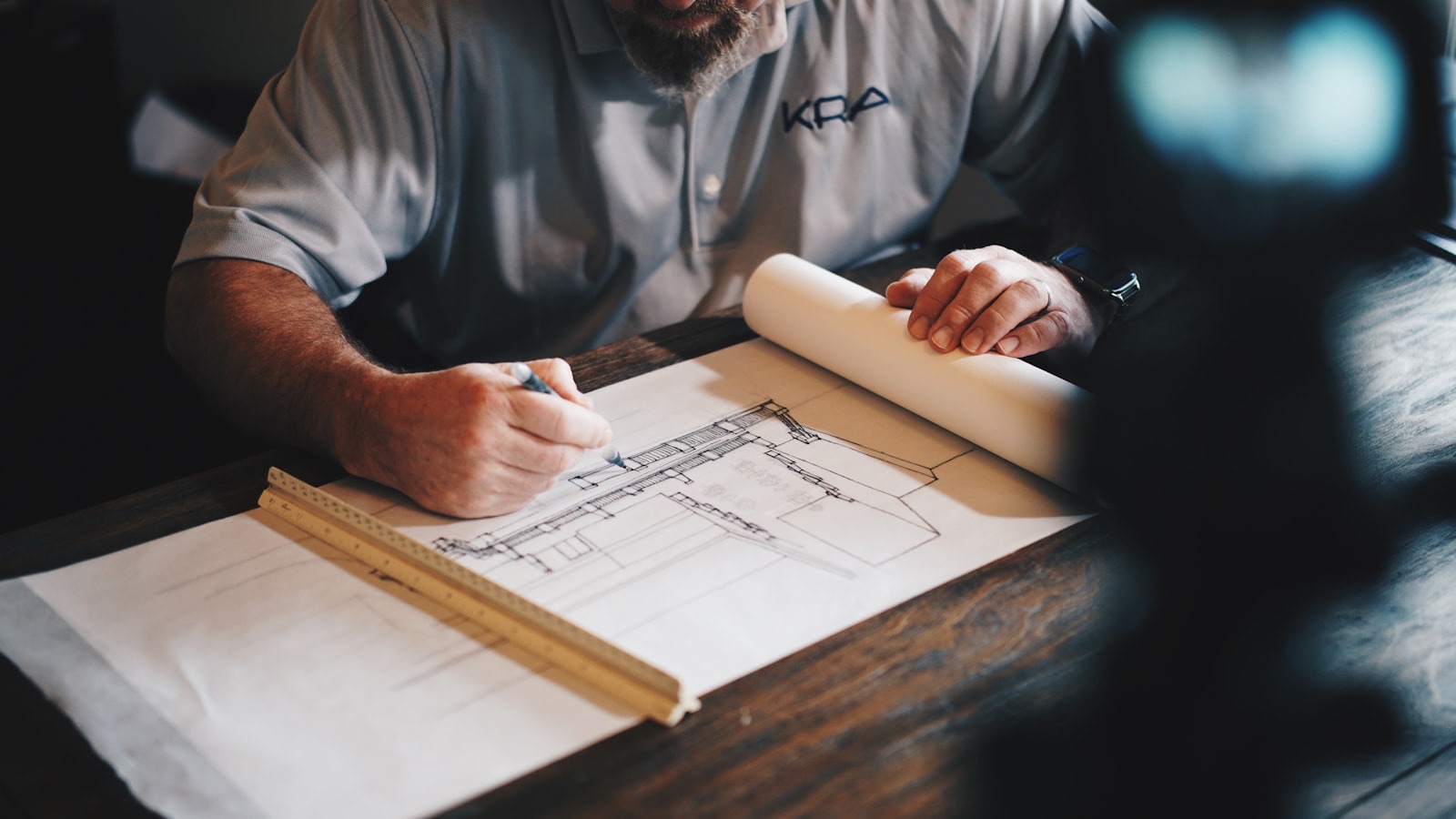 Surveyor drafting a measured building floor plan over architectural drawings